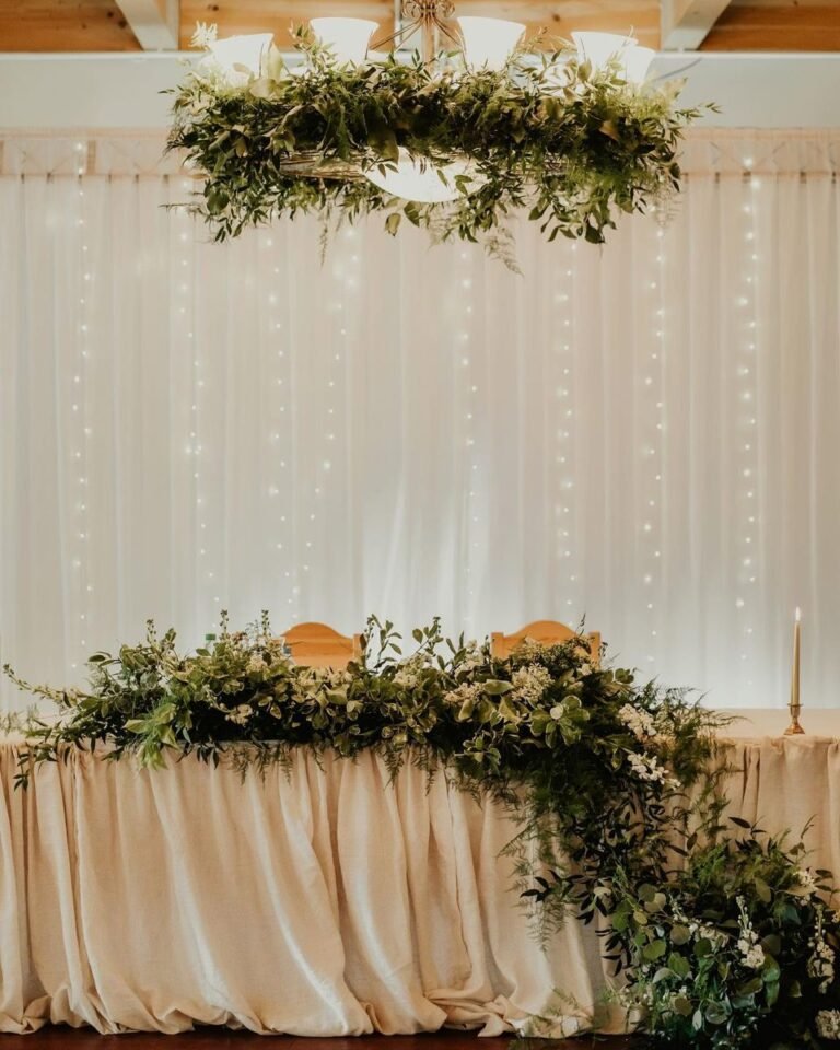 The bride and groom’s table with greenery and fairy lights — OIA Decorations